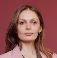 Elegant businesswoman with arms crossed in studio portrait, showcasing leadership and confidence.