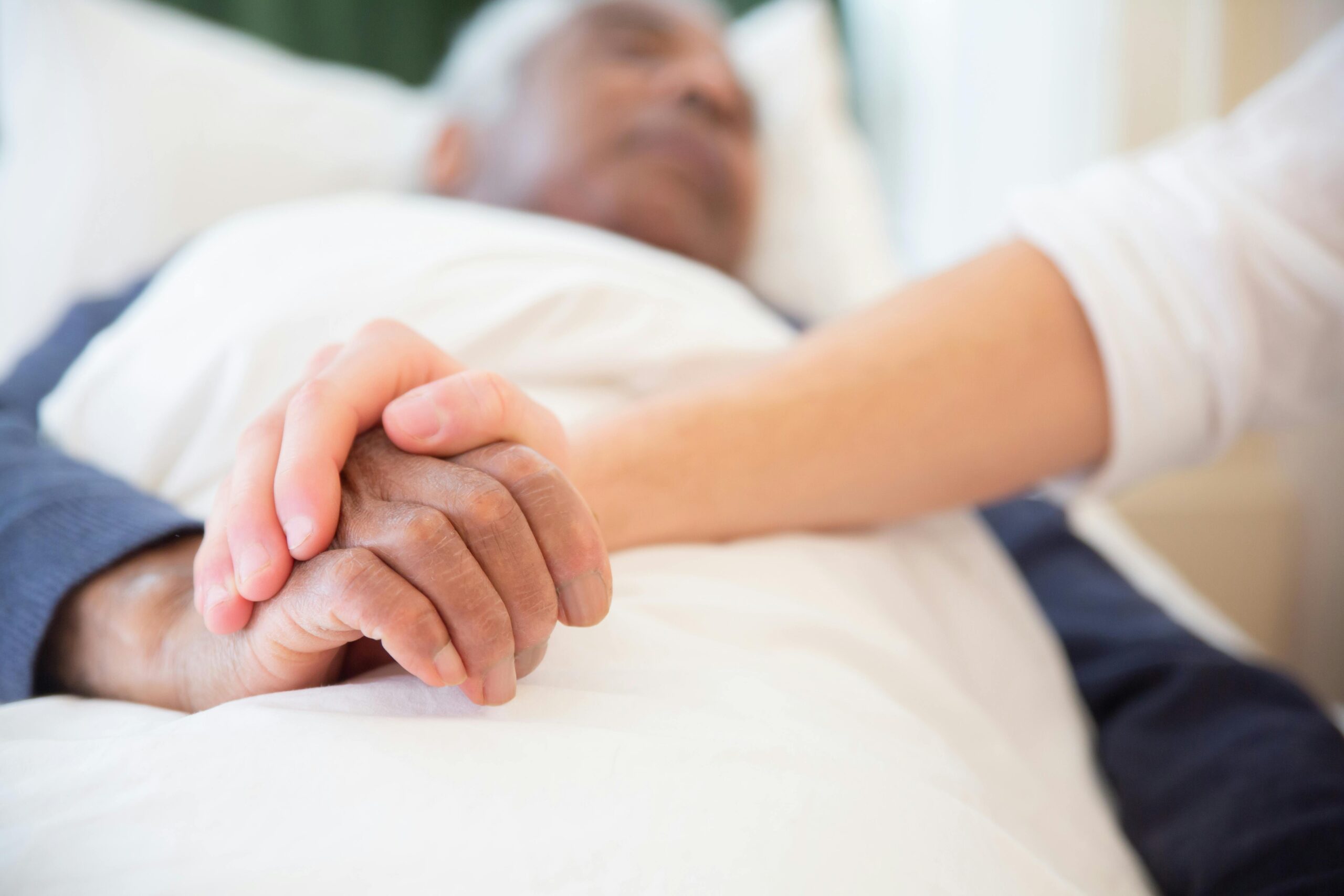 Home A comforting gesture as a hand holds another in a hospital setting, symbolizing care and support.